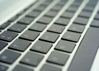 Close-up of a dark laptop keyboard with backlit-style keycaps, shallow depth of field