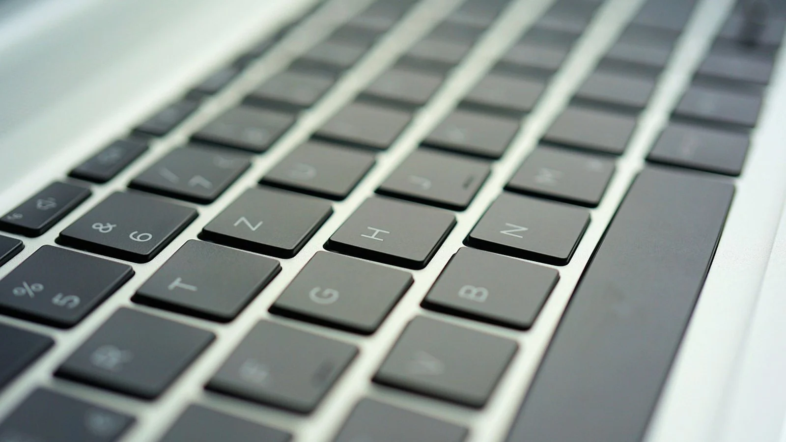 Close-up of a dark laptop keyboard with backlit-style keycaps, shallow depth of field