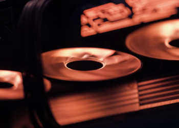 Close-up of spinning graphics card cooling fans lit in orange, RTX logo partially visible
