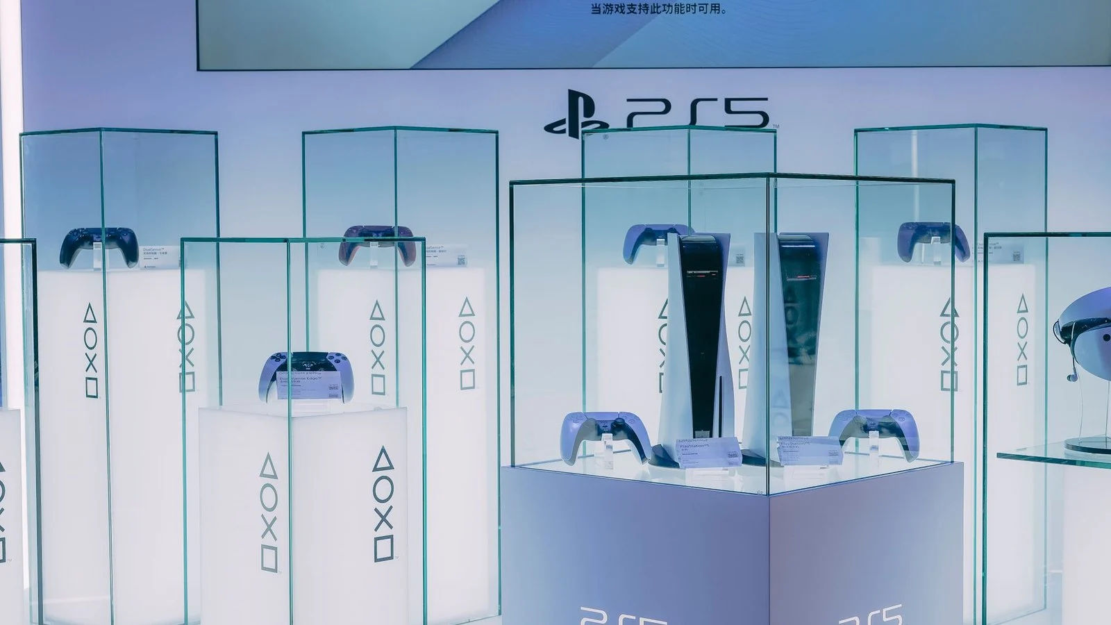 PS5 consoles and DualSense controllers displayed in glass cases at a PlayStation exhibit