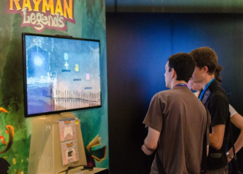 Two people viewing a Rayman Legends demo on a TV at a convention booth