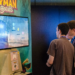 Two people viewing a Rayman Legends demo on a TV at a convention booth