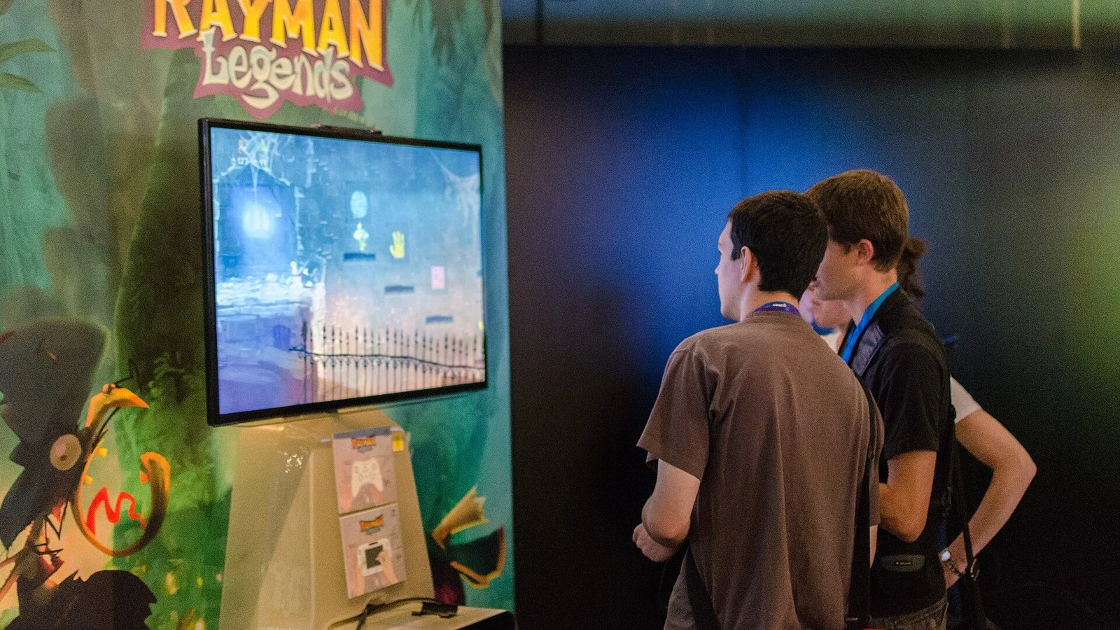 Two people viewing a Rayman Legends demo on a TV at a convention booth
