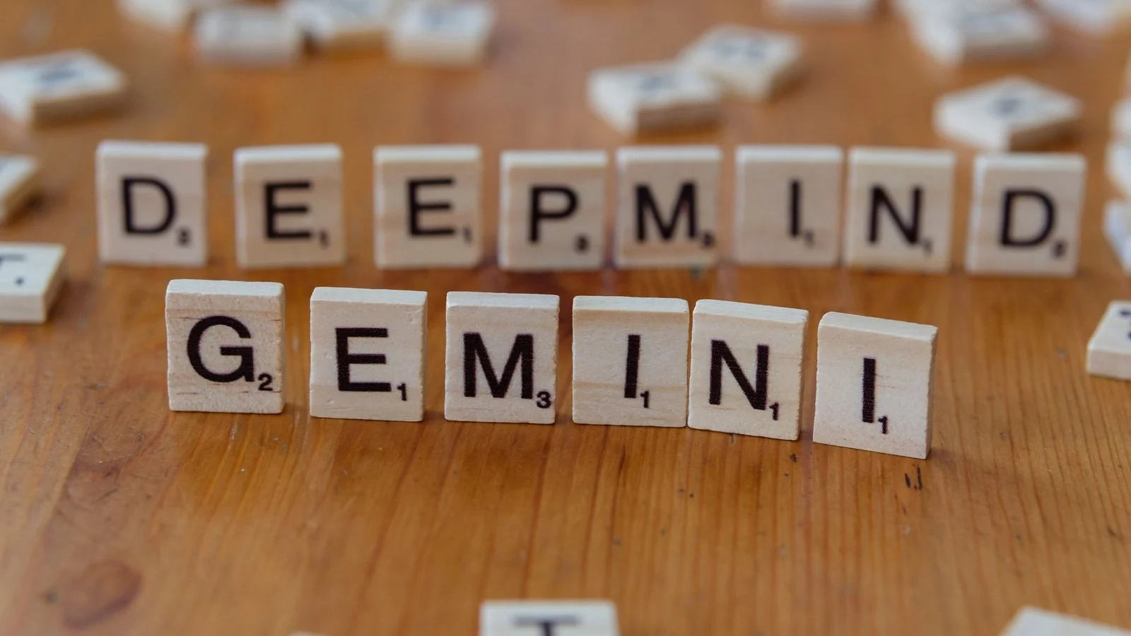 Wooden Scrabble tiles spelling DEEPMIND and GEMINI on a wood table