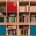 Bookshelf cubes filled with books and two teal cabinet doors, one red door