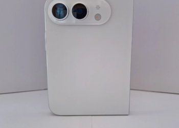 back of a white smartphone standing upright with a pill-shaped dual-camera module and flash