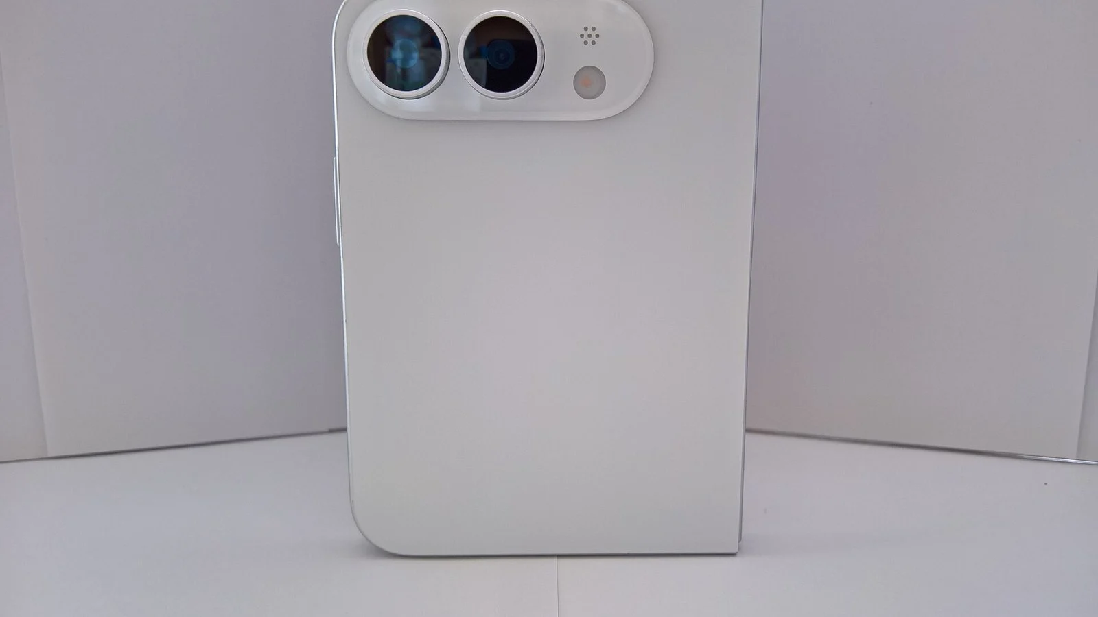 back of a white smartphone standing upright with a pill-shaped dual-camera module and flash