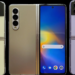Three folding smartphones stand upright, a yellow flip phone, an open gold foldable, and a lilac flip phone