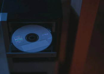 A blank CD-R disc sits in an open optical drive tray of a dark computer case