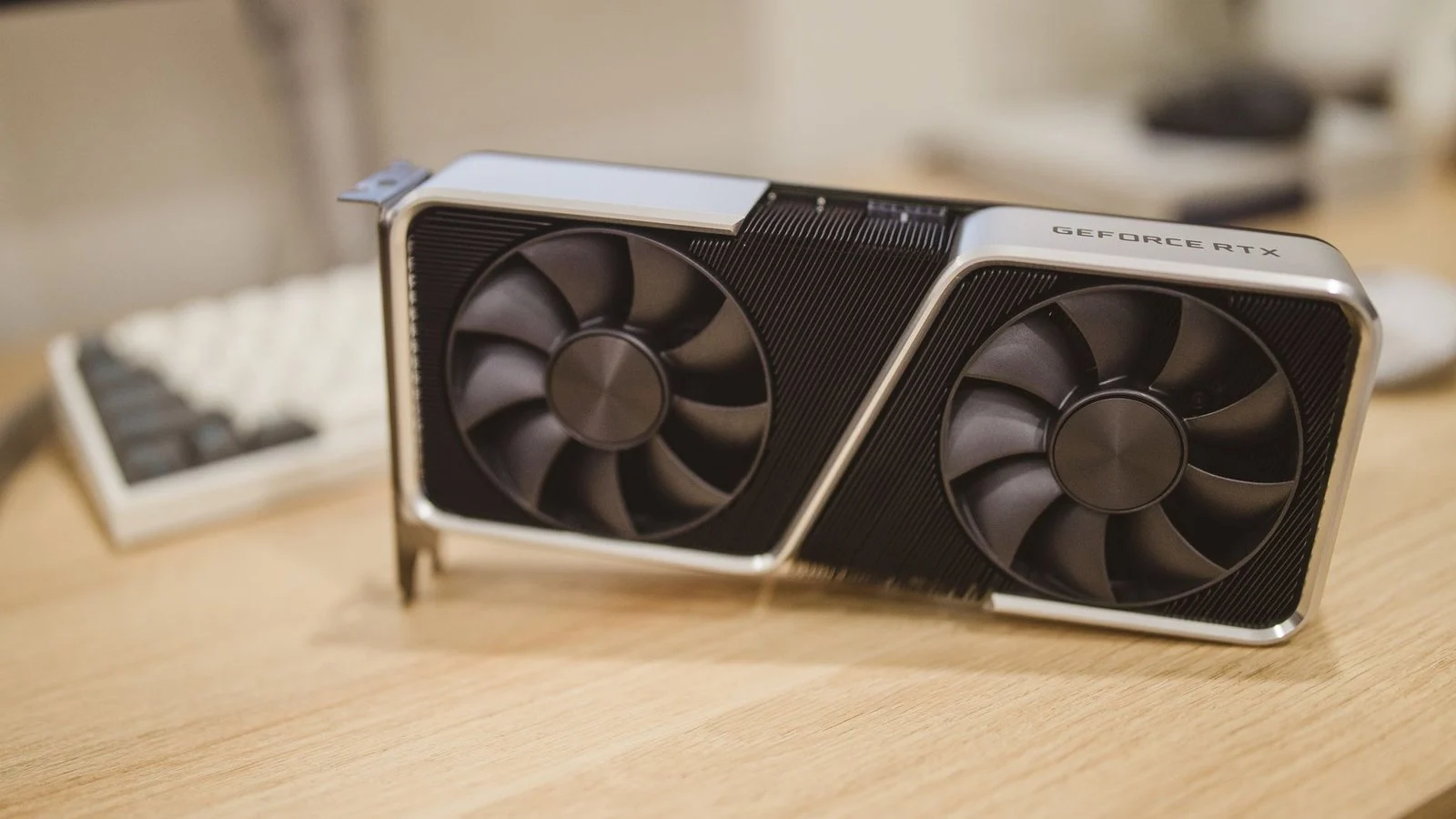 Dual-fan GeForce RTX graphics card with cooler shroud sitting on a wooden desk