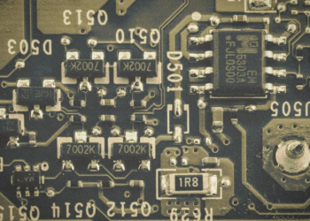 Close-up of a dark green circuit board with small surface-mount components and mirrored silkscreen labels