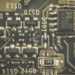 Close-up of a dark green circuit board with small surface-mount components and mirrored silkscreen labels