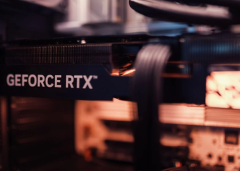 Close-up of a GeForce RTX graphics card heatsink and logo inside a PC case, blurred cables in background