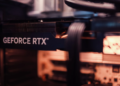 Close-up of a GeForce RTX graphics card installed in a PC case with a blurred power cable bundle