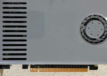 Close-up of a light grey graphics card with one fan and PCI slot, resting on a countertop
