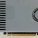 Close-up of a light grey graphics card with one fan and PCI slot, resting on a countertop