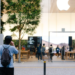 Person photographing the exterior of an Apple Store with illuminated Apple logo