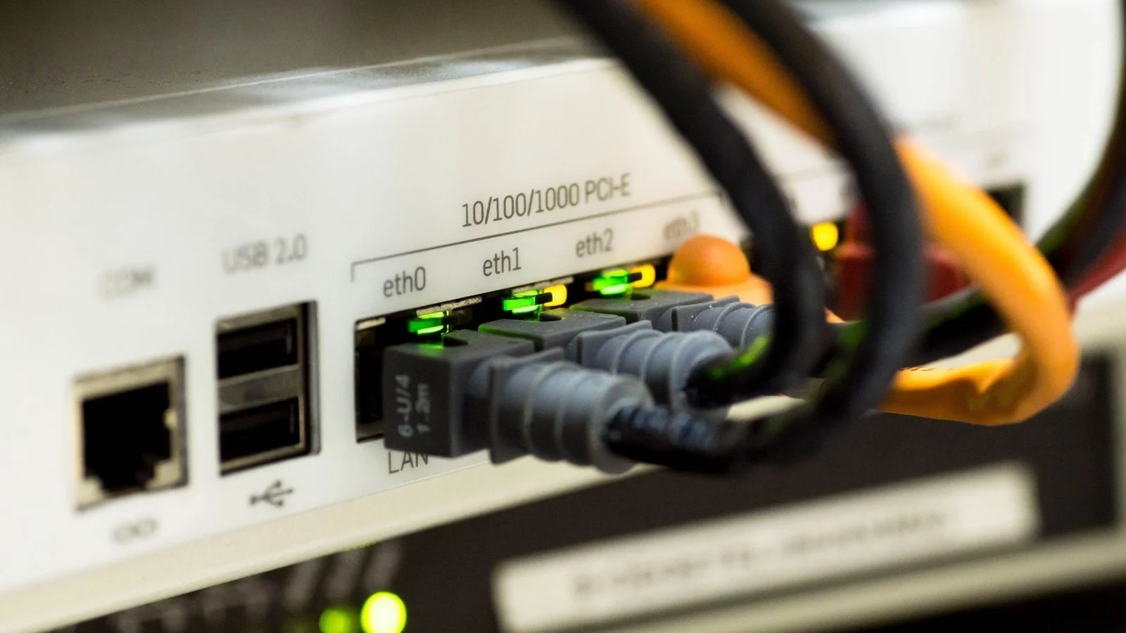 Rear panel of a networking device with USB, COM and ethernet ports connected to patch cables