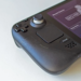 Close-up of a black Steam Deck handheld showing its D-pad, trackpad, and Steam button