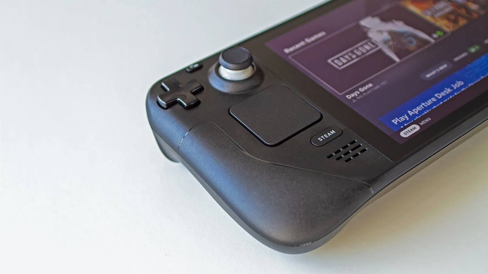 Close-up of a black Steam Deck handheld showing its D-pad, trackpad, and Steam button