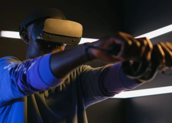 Man wearing a dark VR headset and holding motion controllers, arms extended forward