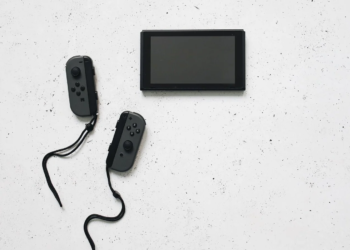 Nintendo Switch console with detached grey Joy-Con controllers on a speckled white surface