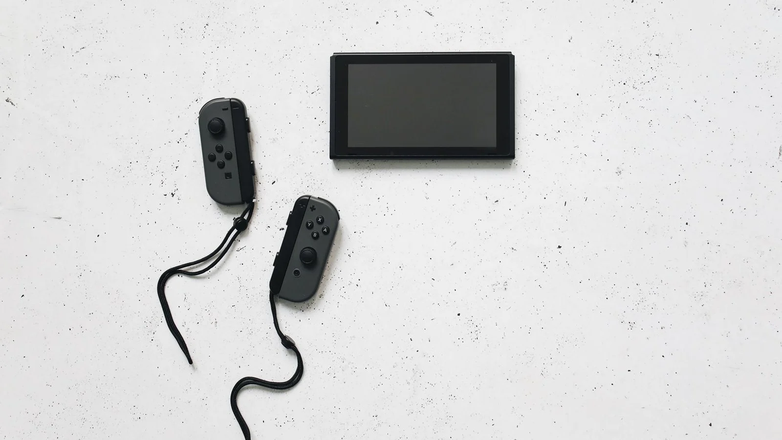 Nintendo Switch console with detached grey Joy-Con controllers on a speckled white surface