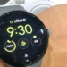 A round black Google Pixel Watch on a wrist showing time, date, steps and heart rate