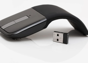 Microsoft Arc Mouse folding wireless mouse beside its USB nano receiver on white background