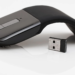 Microsoft Arc Mouse folding wireless mouse beside its USB nano receiver on white background