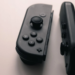 Two black Nintendo Switch Joy-Con controllers lying detached on a light surface