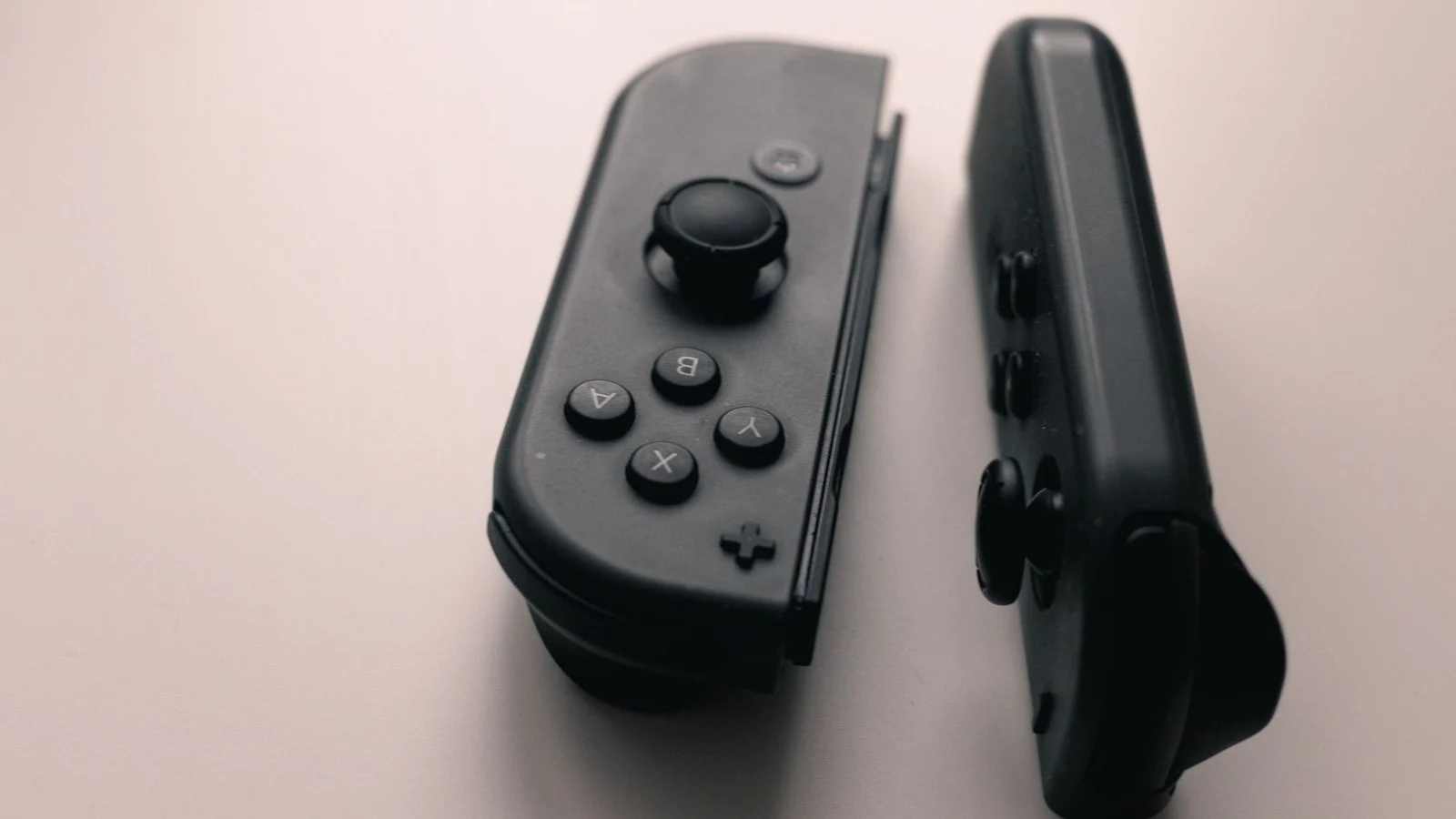 Two black Nintendo Switch Joy-Con controllers lying detached on a light surface