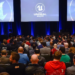 Audience at a conference watching the Unreal Engine logo displayed on three large screens
