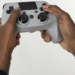 Hands holding a generic gray game controller against a white background