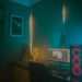 Dim room with neon lightning sign, PC tower with red fans, and a desktop monitor showing an unrelated image