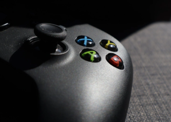 Close-up of a black Xbox controller's ABXY buttons and joystick on a fabric couch
