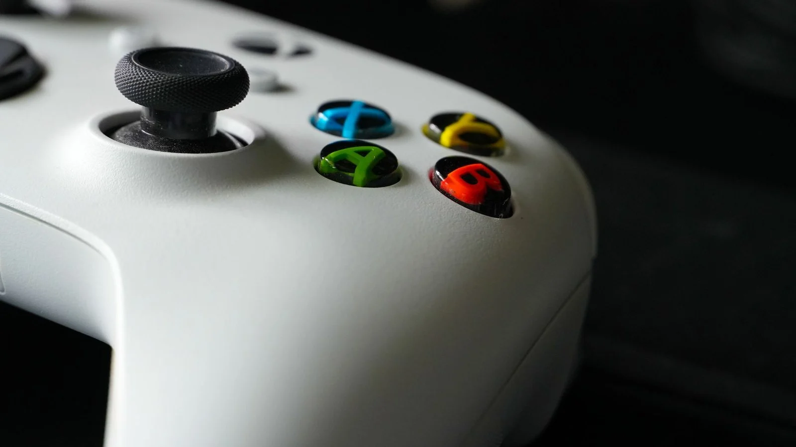 Close-up of a white game controller's thumbstick and colored A, B, X, Y buttons