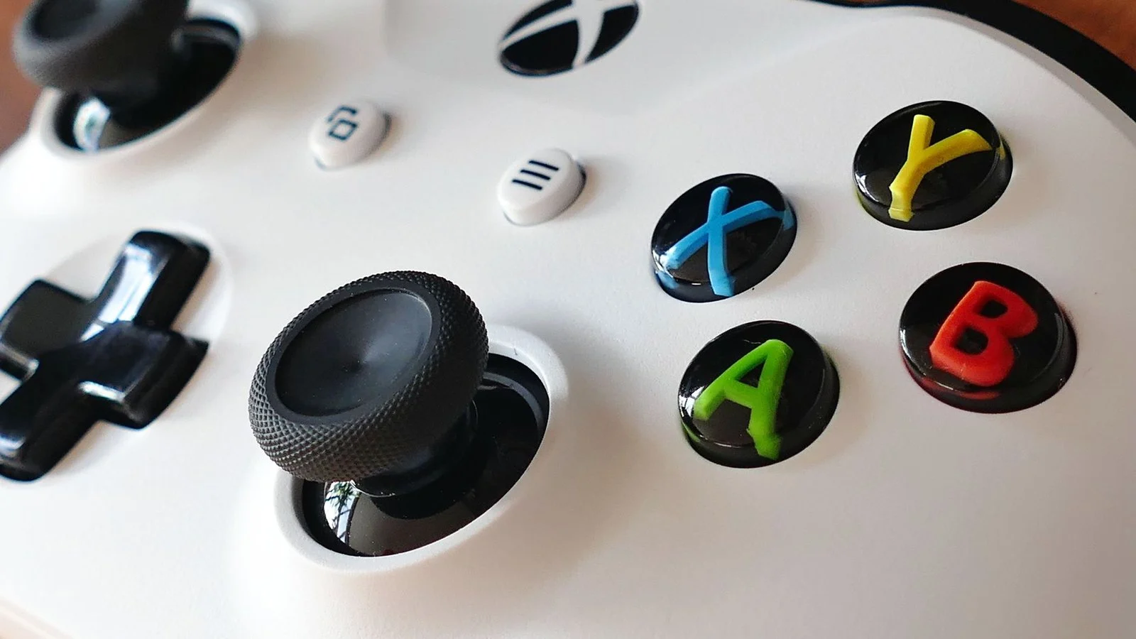 Close-up of a white Xbox controller showing the A, B, X, Y face buttons and joystick