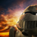 Weathered bronze robotic helmet with a circular lamp, lit against a dramatic sunset sky