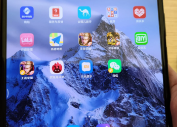 Close-up of a smartphone home screen with Chinese app icons, held in a hand