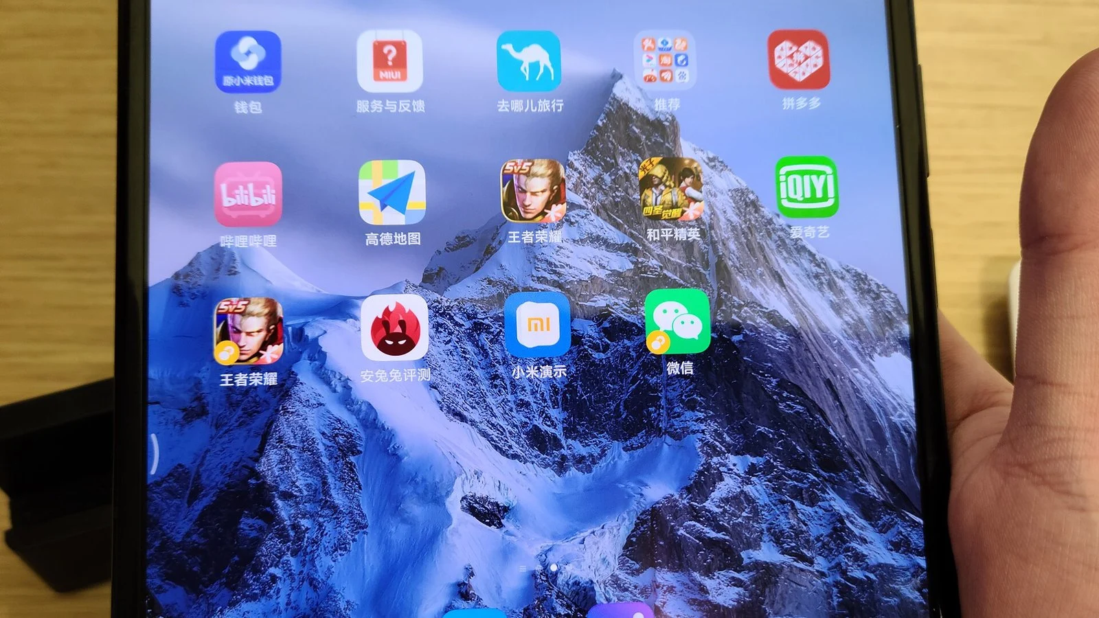 Close-up of a smartphone home screen with Chinese app icons, held in a hand