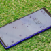 Blue Sony Xperia smartphone lying face-up on artificial grass showing a lock screen clock
