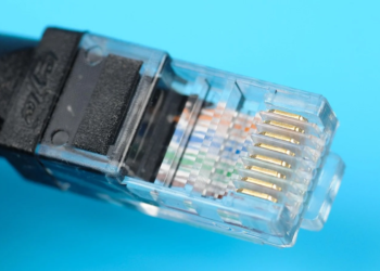 Close-up of a clear RJ45 Ethernet connector on a cable against a cyan background
