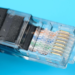 Close-up of a clear RJ45 Ethernet connector on a cable against a cyan background