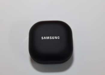 Black Samsung earbuds charging case with white Samsung logo, closed, on a gray surface
