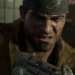 Close-up of a bloodied man in a leather jacket gripping a makeshift weapon, gritting his teeth
