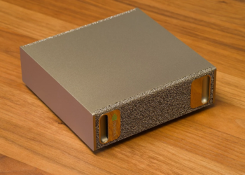 NVIDIA DGX Spark compact metal desktop AI computer with gold textured mesh end panel on wood surface