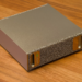 NVIDIA DGX Spark compact metal desktop AI computer with gold textured mesh end panel on wood surface