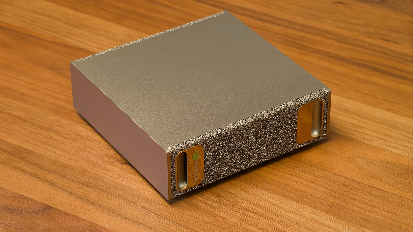 NVIDIA DGX Spark compact metal desktop AI computer with gold textured mesh end panel on wood surface